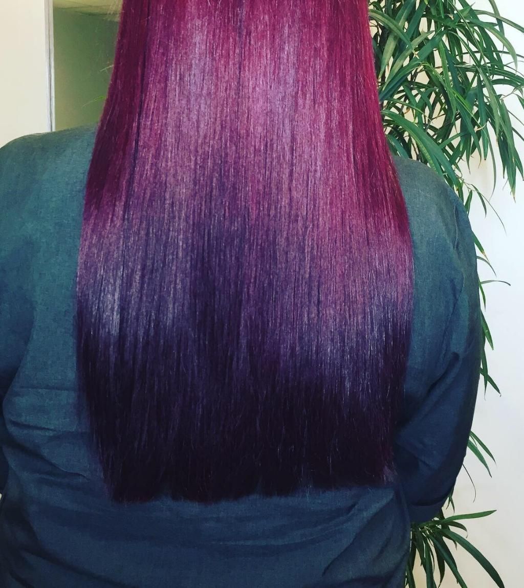 A Woman With Purple Hair Is Standing In Front Of A Plant — Fuse Hair & Beauty In Darwin City, NT