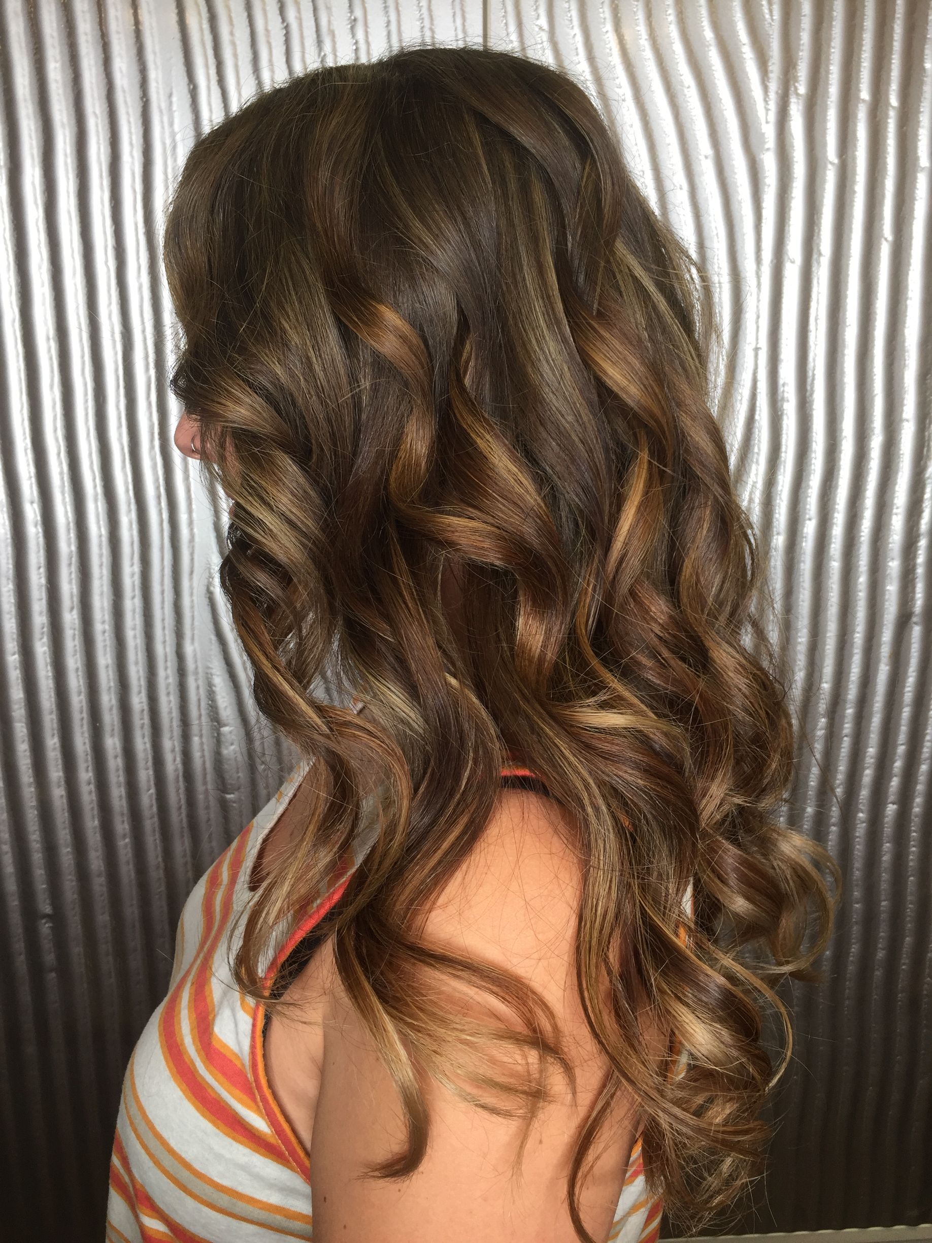 A Woman With Long Brown Hair Is Standing In Front Of A Metal Wall — Fuse Hair & Beauty In Darwin City, NT