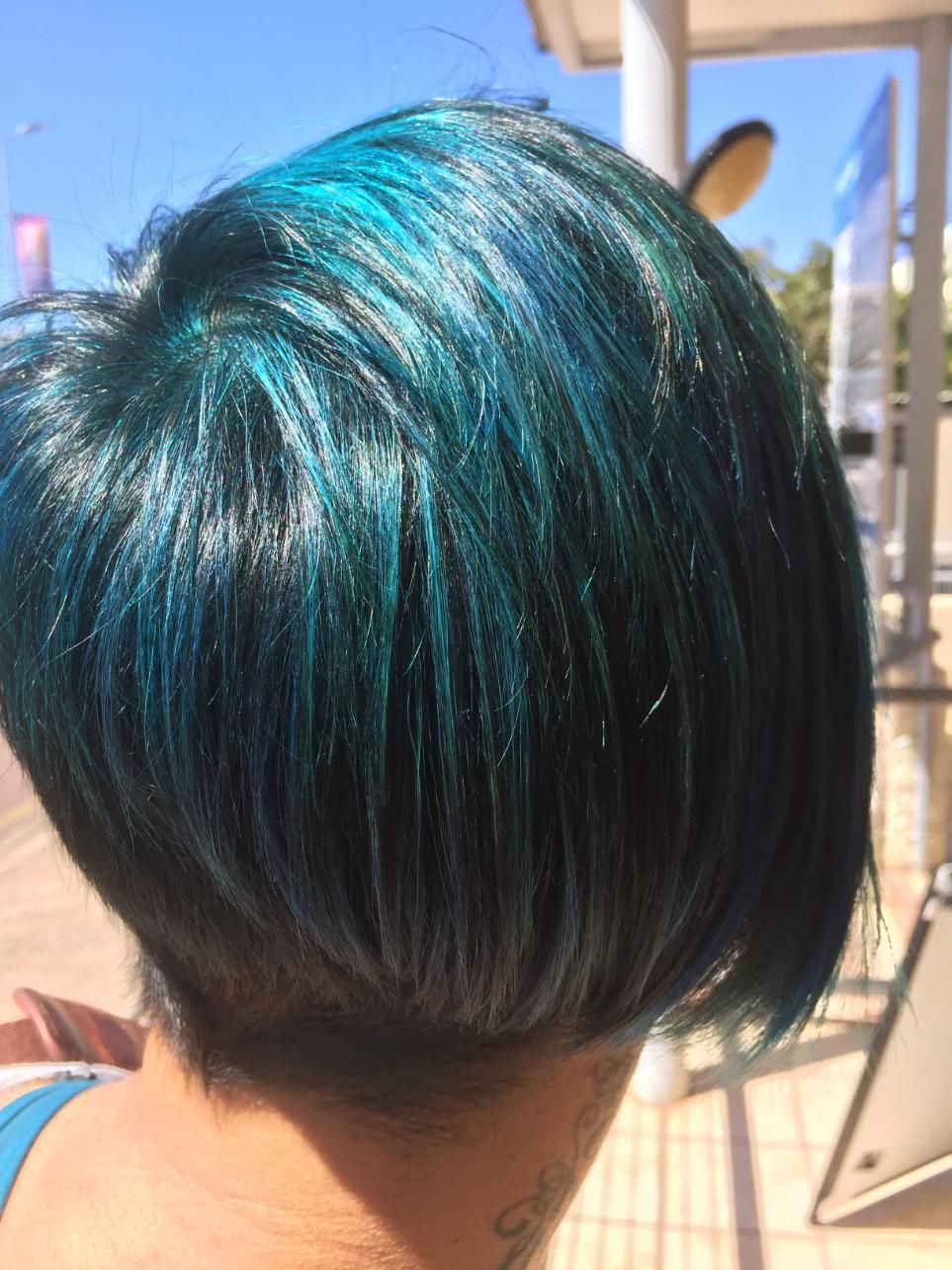 A Woman With Short Blue Hair Is Standing In Front Of A Bus Stop — Fuse Hair & Beauty In Darwin City, NT