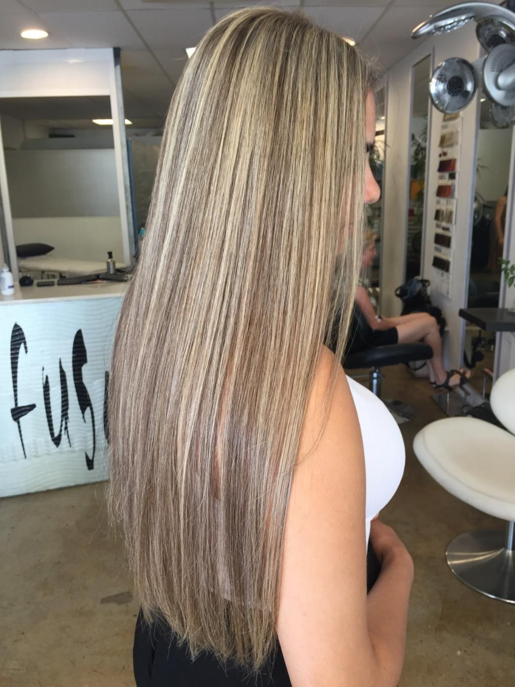 A Woman With Long Blonde Hair Is Standing In A Salon — Fuse Hair & Beauty In Darwin City, NT
