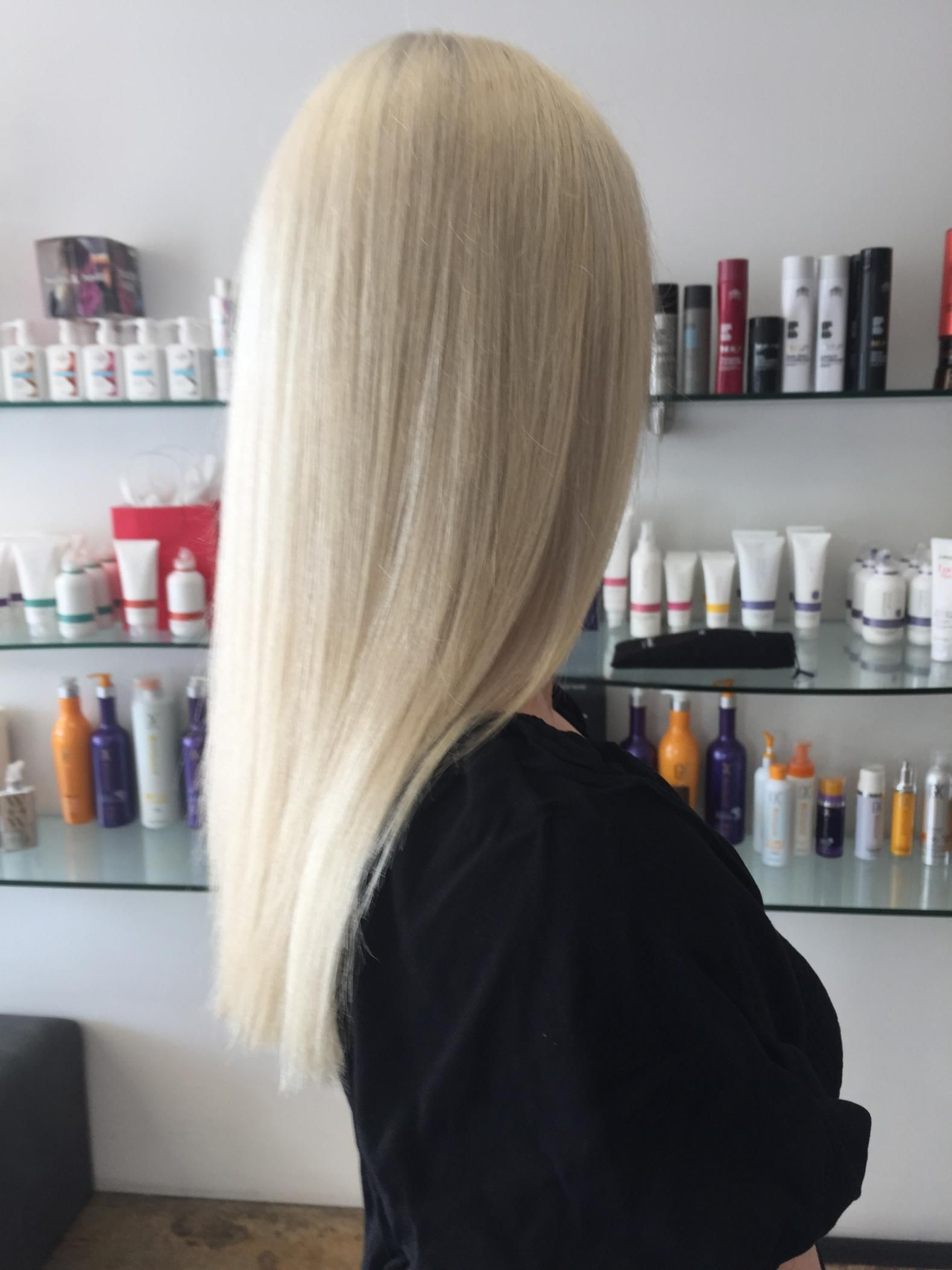 A Woman With Blonde Hair Is Standing In Front Of A Display Of Hair Products — Fuse Hair & Beauty In Darwin City, NT