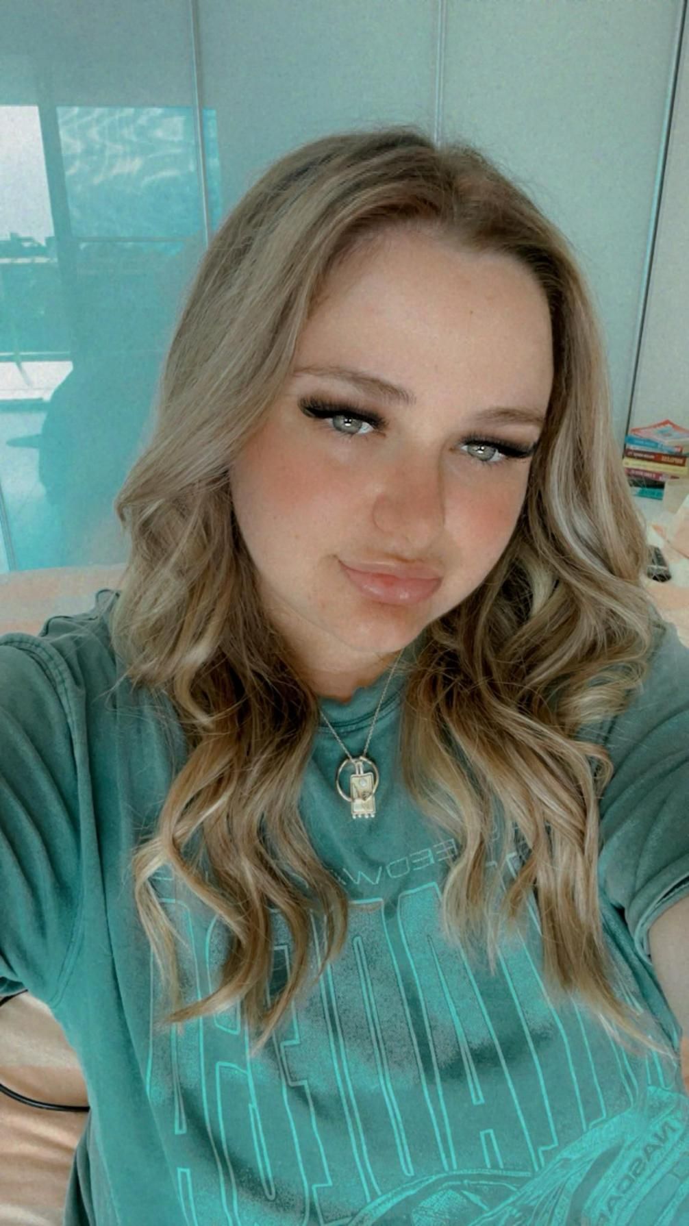 A Woman In A Green Shirt Is Taking A Selfie Of  Her Hair — Fuse Hair & Beauty In Darwin City, NT