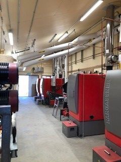 A row of red and gray boilers are lined up in a room.