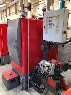 A large red and gray boiler is sitting in a room.