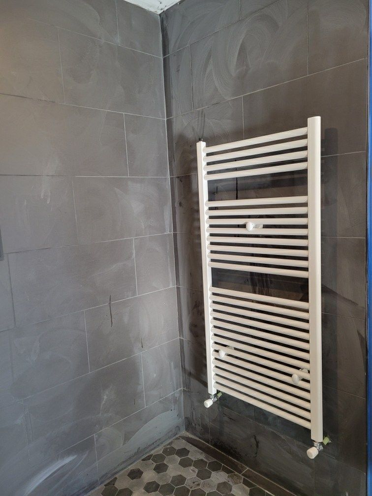 A white towel rack is hanging on a wall in a bathroom.