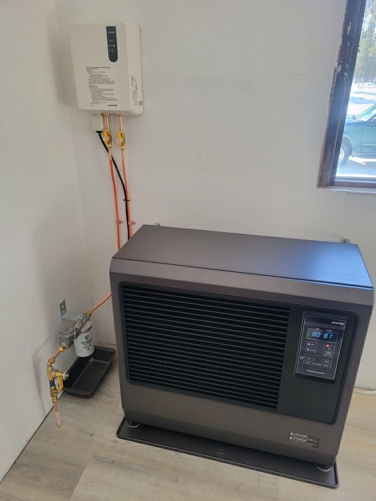A heater is sitting in a corner of a room next to a window.
