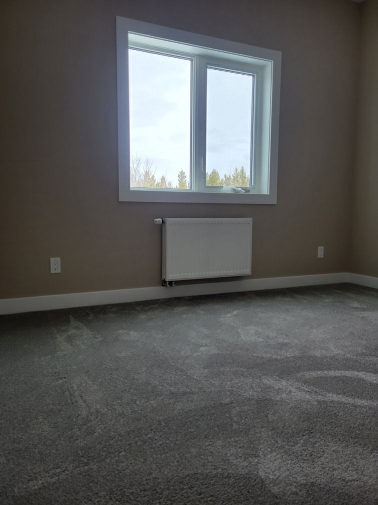 An empty room with a window and a radiator.