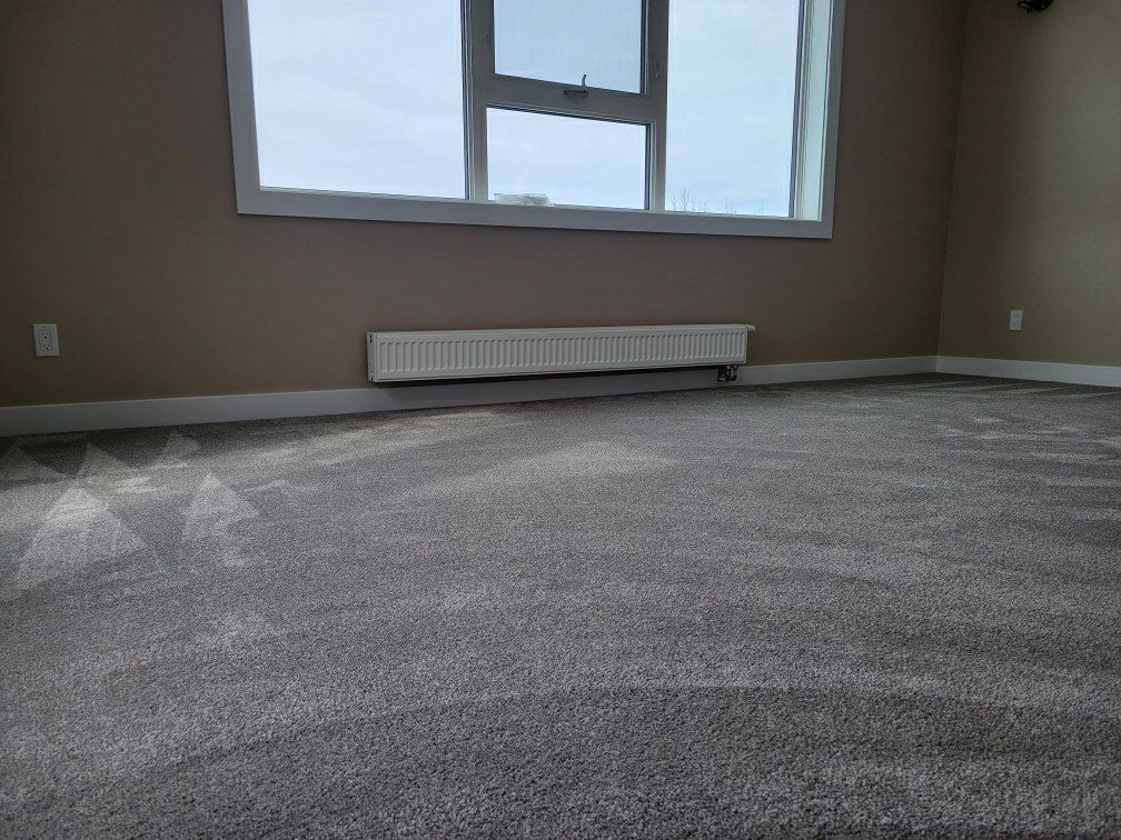 An empty room with a window and a radiator on the floor.