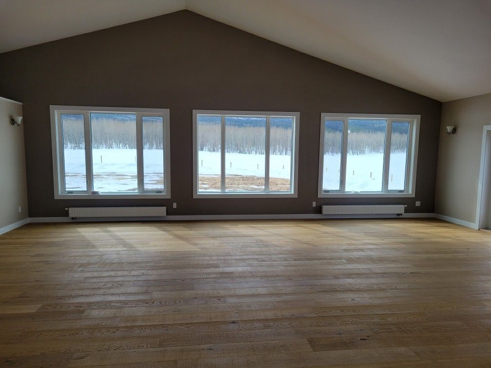An empty room with a vaulted ceiling and lots of windows