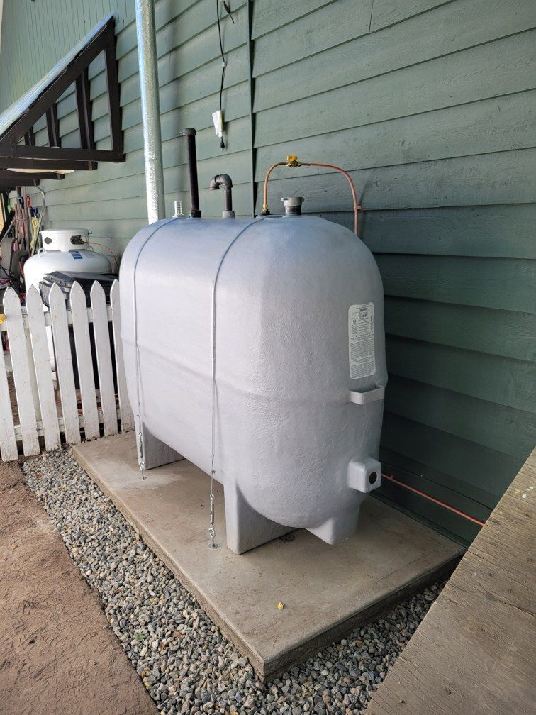 A propane tank is sitting on a concrete platform outside of a house.
