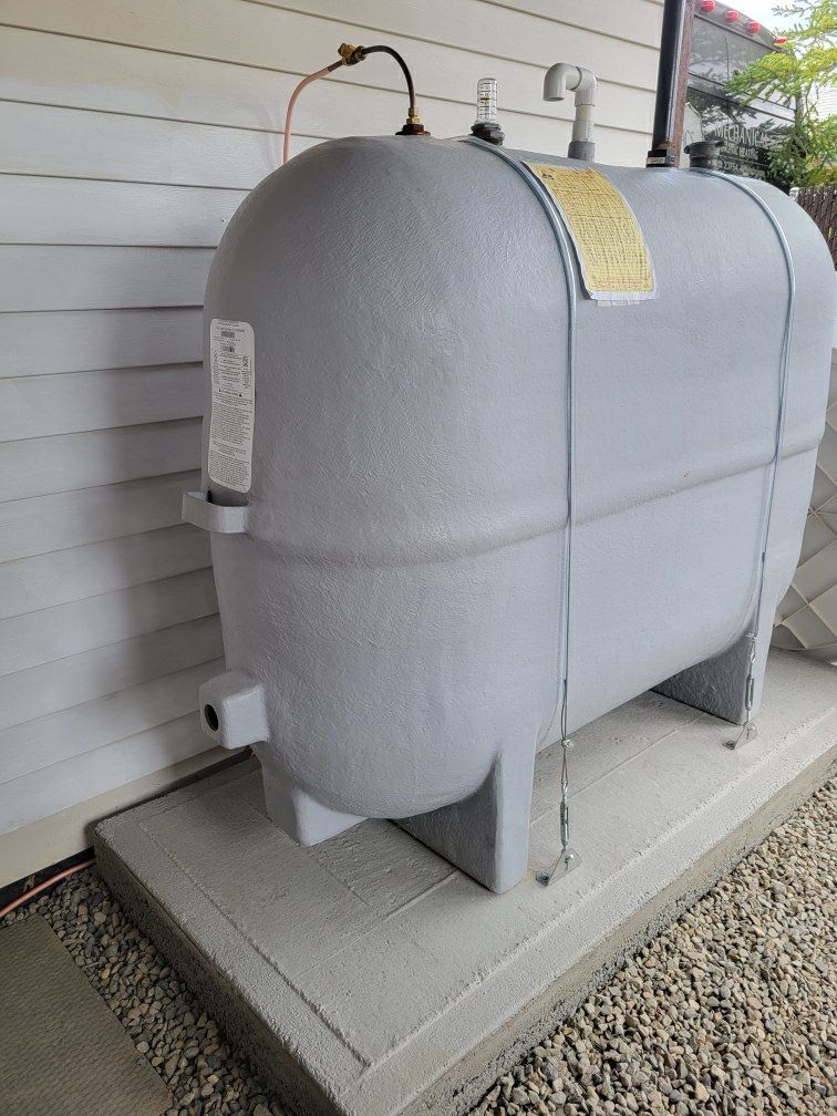 A large gray propane tank is sitting on the side of a house.