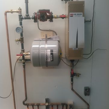A water heater is connected to a wall with copper pipes.