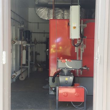 A red machine is sitting inside of a building next to a door.