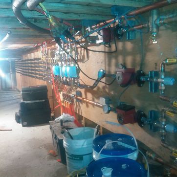 A bunch of pipes are hanging on a wall in a basement.