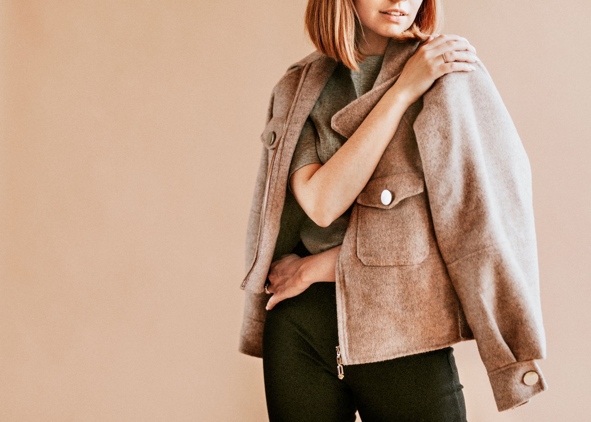 A woman is wearing a brown jacket and black pants.