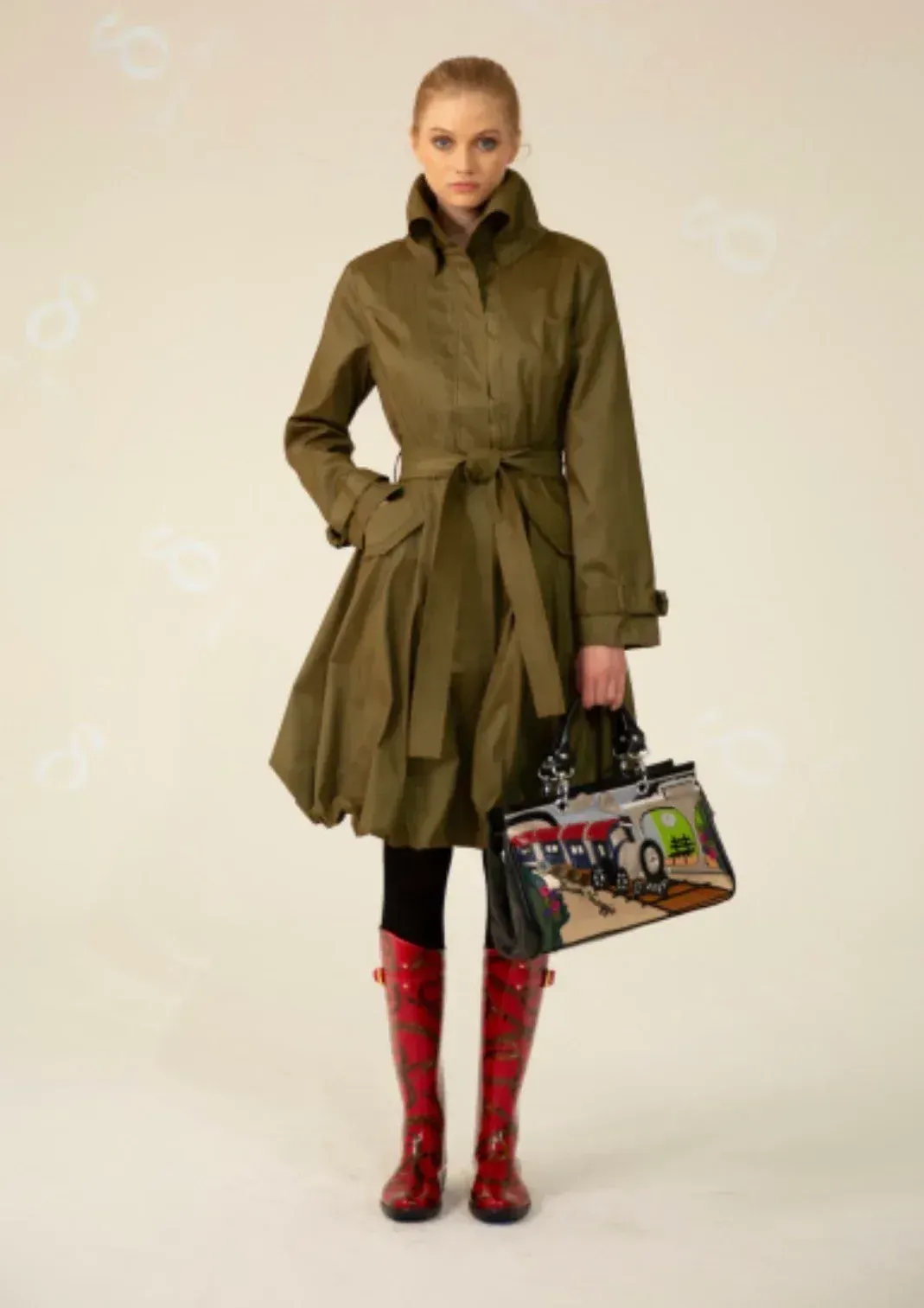 A woman in a green coat and red boots is holding a bag