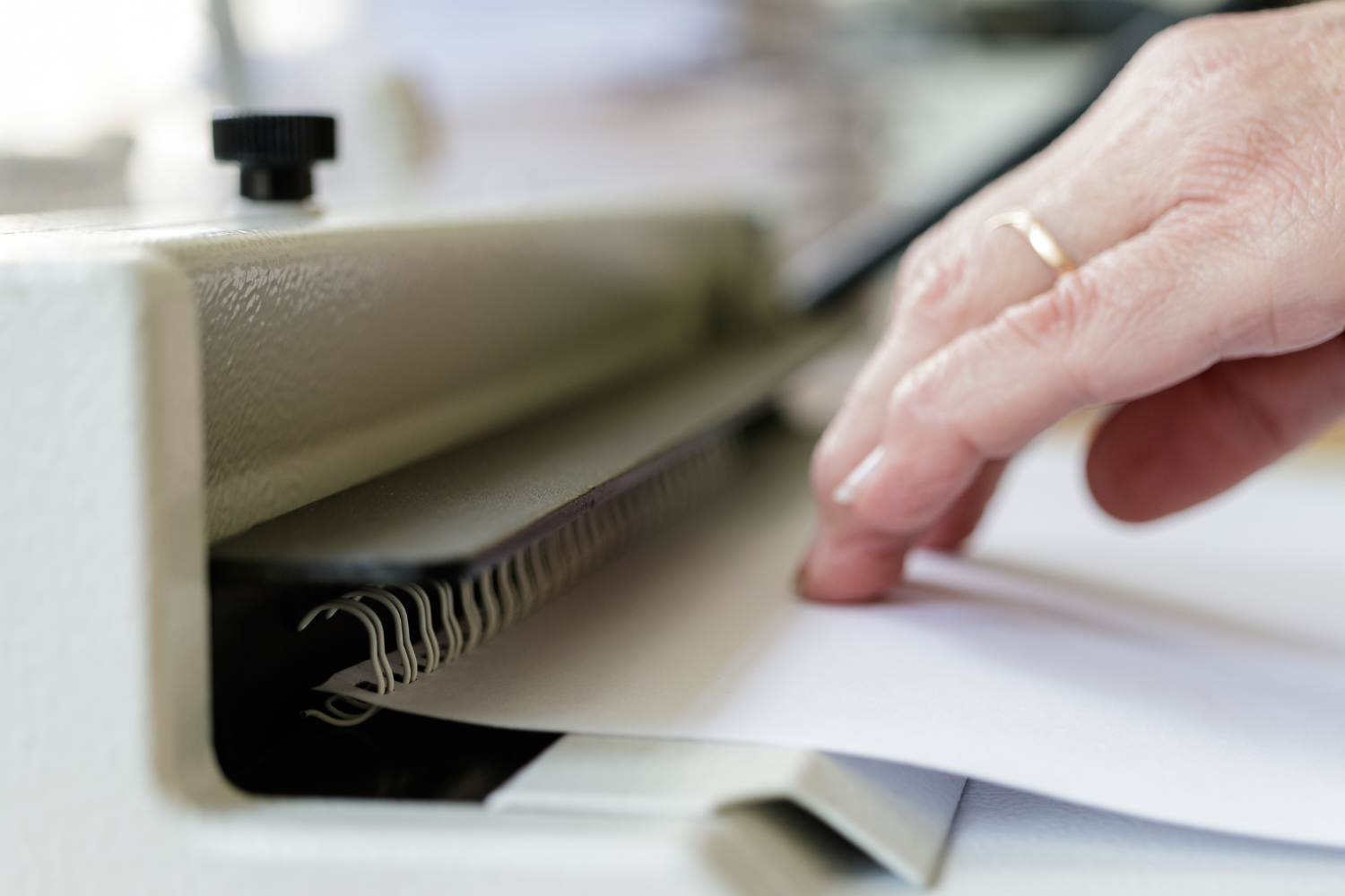 A person is using a machine to bind a piece of paper