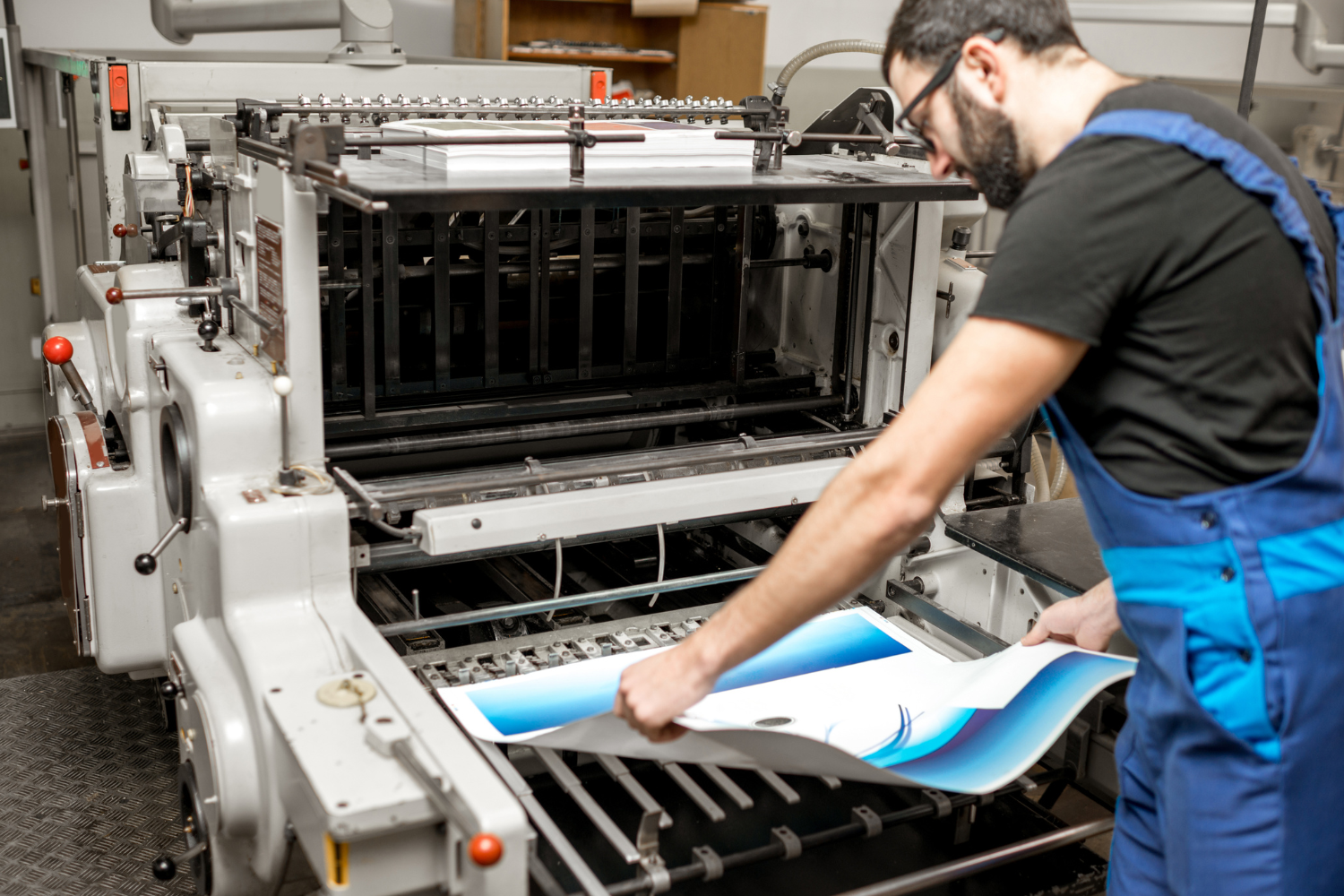 A man is working on a printing machine in a factory.