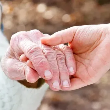 A close up of a person holding an older person 's hand.