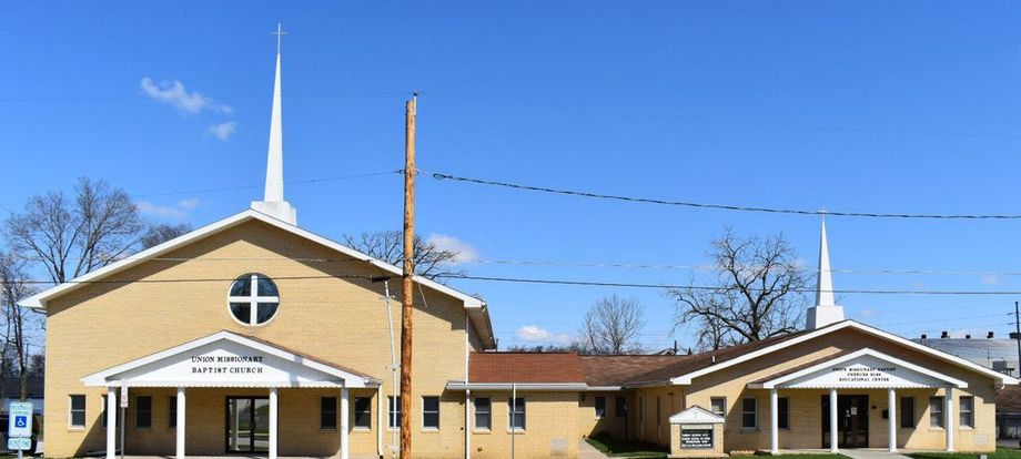 A light-yellow church building with two steeples under a bright blue sky.