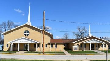 Yellow brick church buildings with steeples under a blue sky.