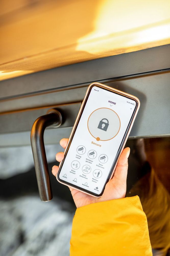 A Person is Holding a Cell Phone in Their Hand in Front of a Fireplace — Adept Security In Wollongong, NSW