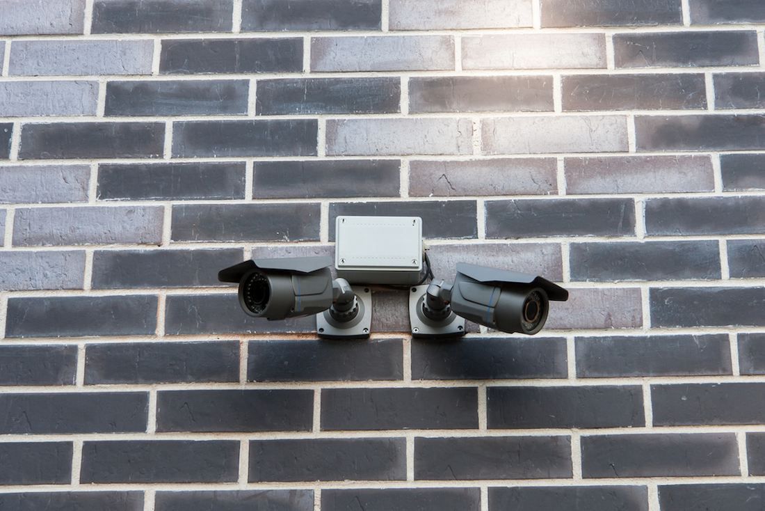 Two Security Cameras Are Mounted on a Brick Wall — Adept Security In Oak Flats, NSW