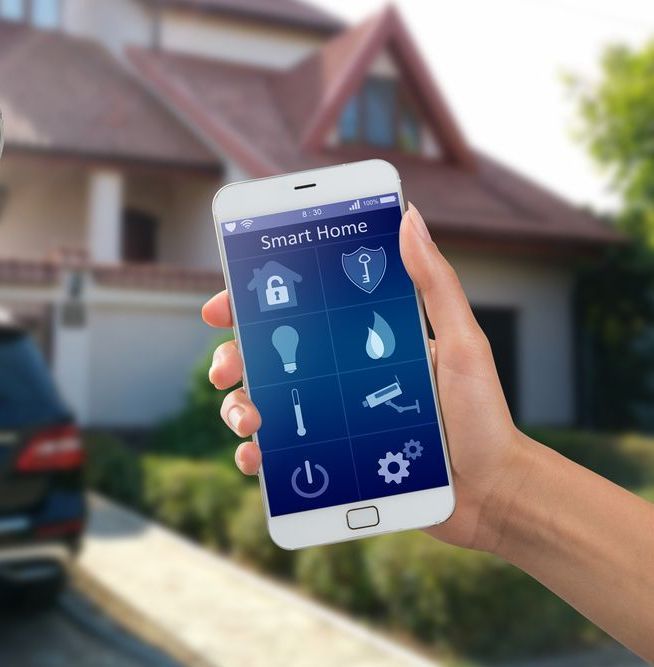 A Person is Holding a Smart Home Phone in Front of a House — Adept Security In Oak Flats, NSW