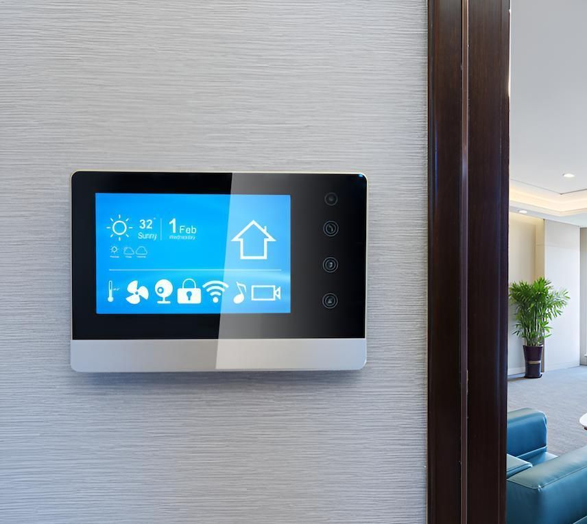 A Smart Home Thermostat is Hanging on a Wall Next to a Door — Adept Security In Wollongong, NSW