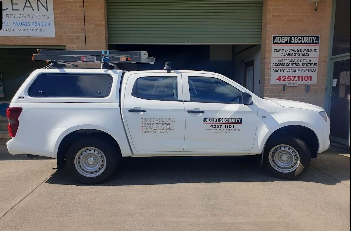 A White Truck With a Canopy is Parked in Front of a Building — Adept Security In Oak Flats, NSW