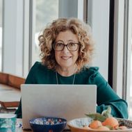 A woman is sitting at a table using a laptop computer.