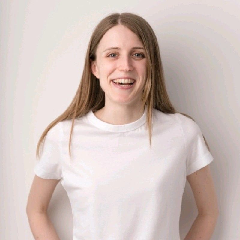 A woman is wearing a white t-shirt and smiling.