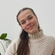 A woman wearing a sweater and earrings is smiling for the camera.