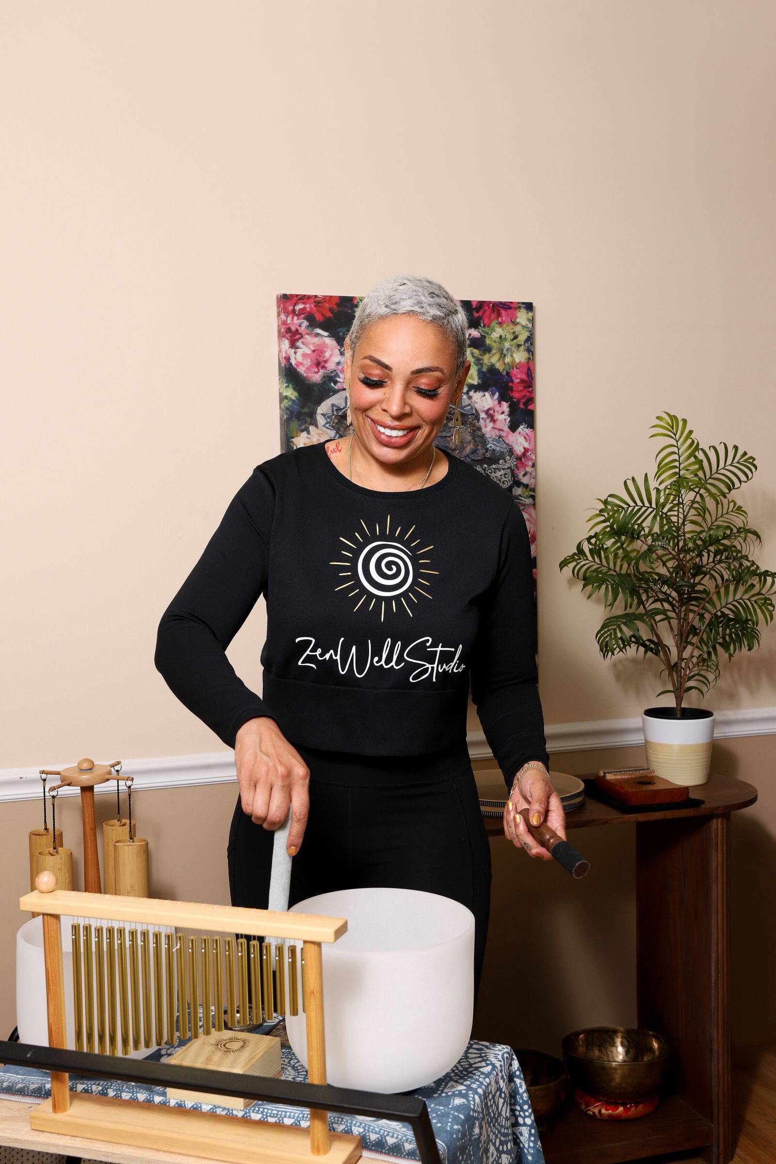 A woman is playing a sound bowl in a living room.