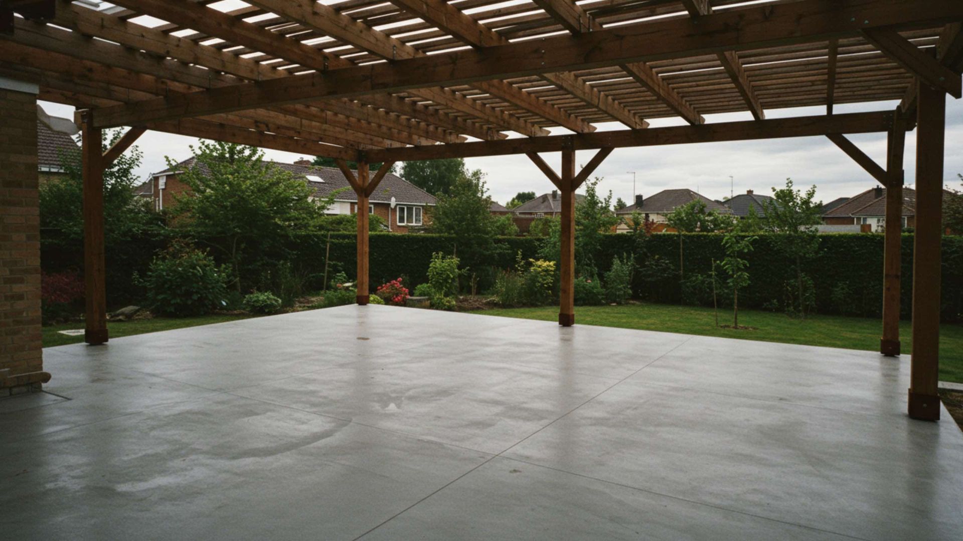 A spacious covered patio with a wooden pergola overhead, looking out onto a green lawn and suburban neighborhood.
