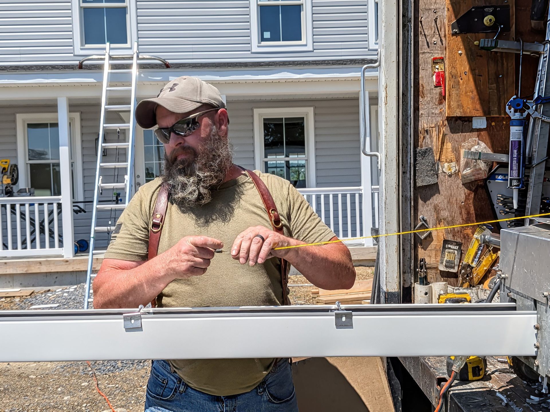 Hands installing a window frame with a drill near a bright green outdoor view.