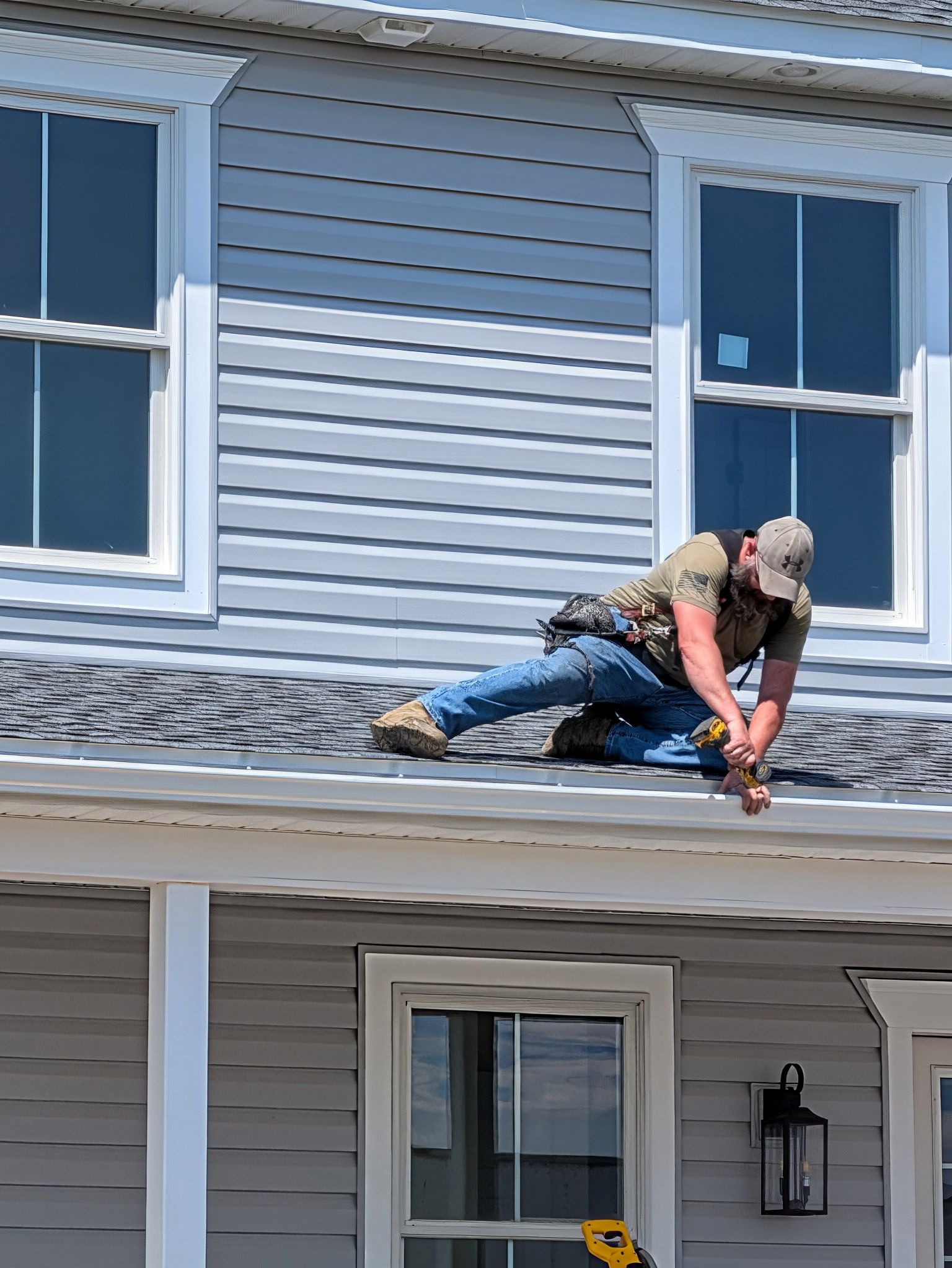Hands installing a brown downspout elbow on a wooden wall outdoors. Hands installing a brown downspout elbow on a wooden wall outdoors.