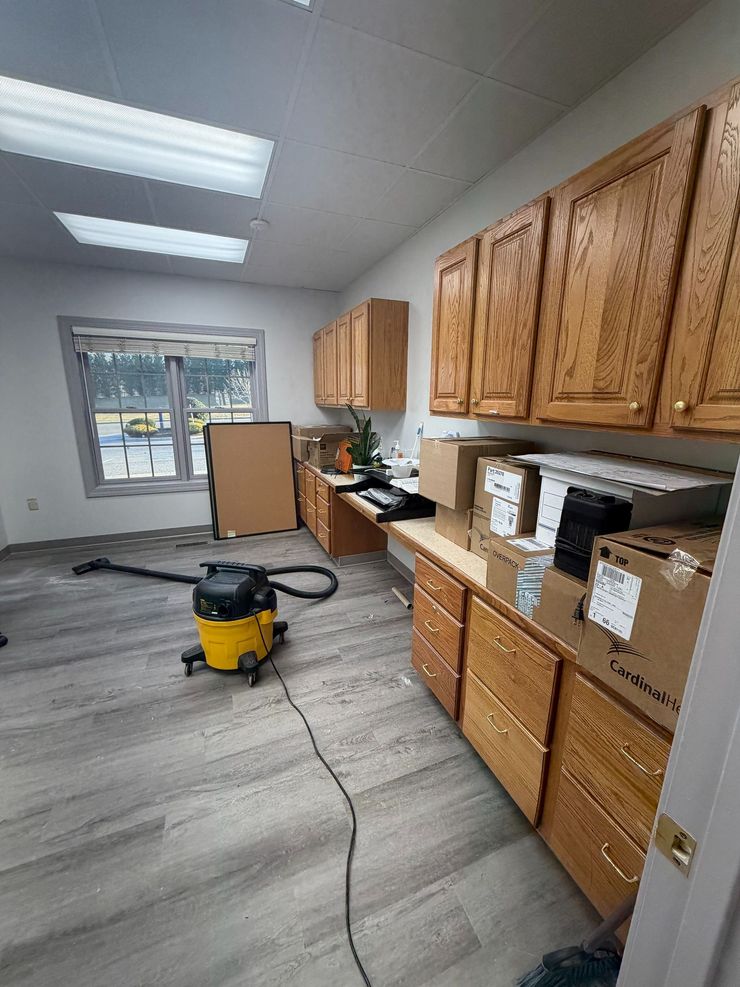 Upholstery cleaner vacuuming a light gray sofa and ottoman in a living room