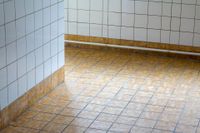 Glossy tiled lobby floor with sunlight reflections and vertical glass or metal railings