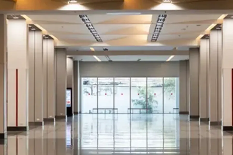 Empty modern lobby with glossy floor, glass doors, and bright overhead lighting