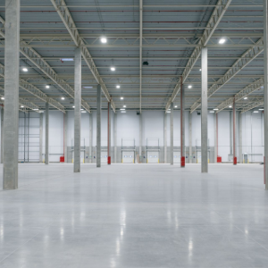 Empty industrial warehouse interior with polished concrete floor and red support columns