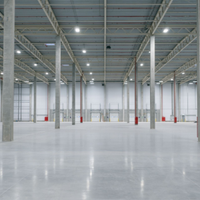 Empty industrial warehouse interior with polished concrete floor and red support columns