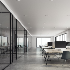 Modern open-plan office with glass walls, desks, and large windows in a bright minimalist space