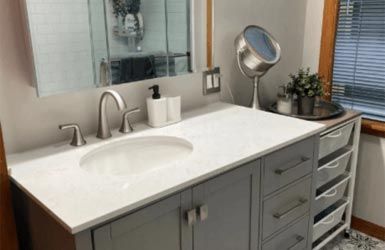 A bathroom with a sink , mirror and drawers.