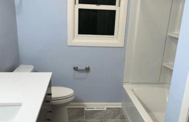 A bathroom with a toilet , sink , tub and window.