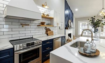 A kitchen with blue cabinets , stainless steel appliances , a sink , and a stove.