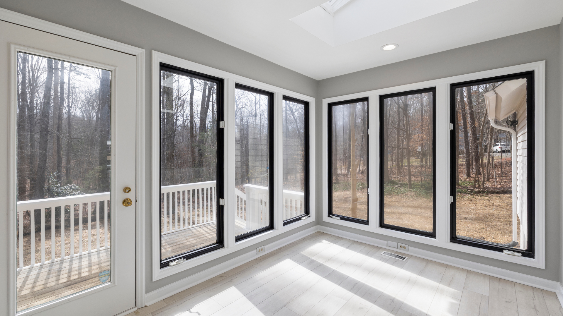An empty sun room with lots of windows and doors leading to a deck.
