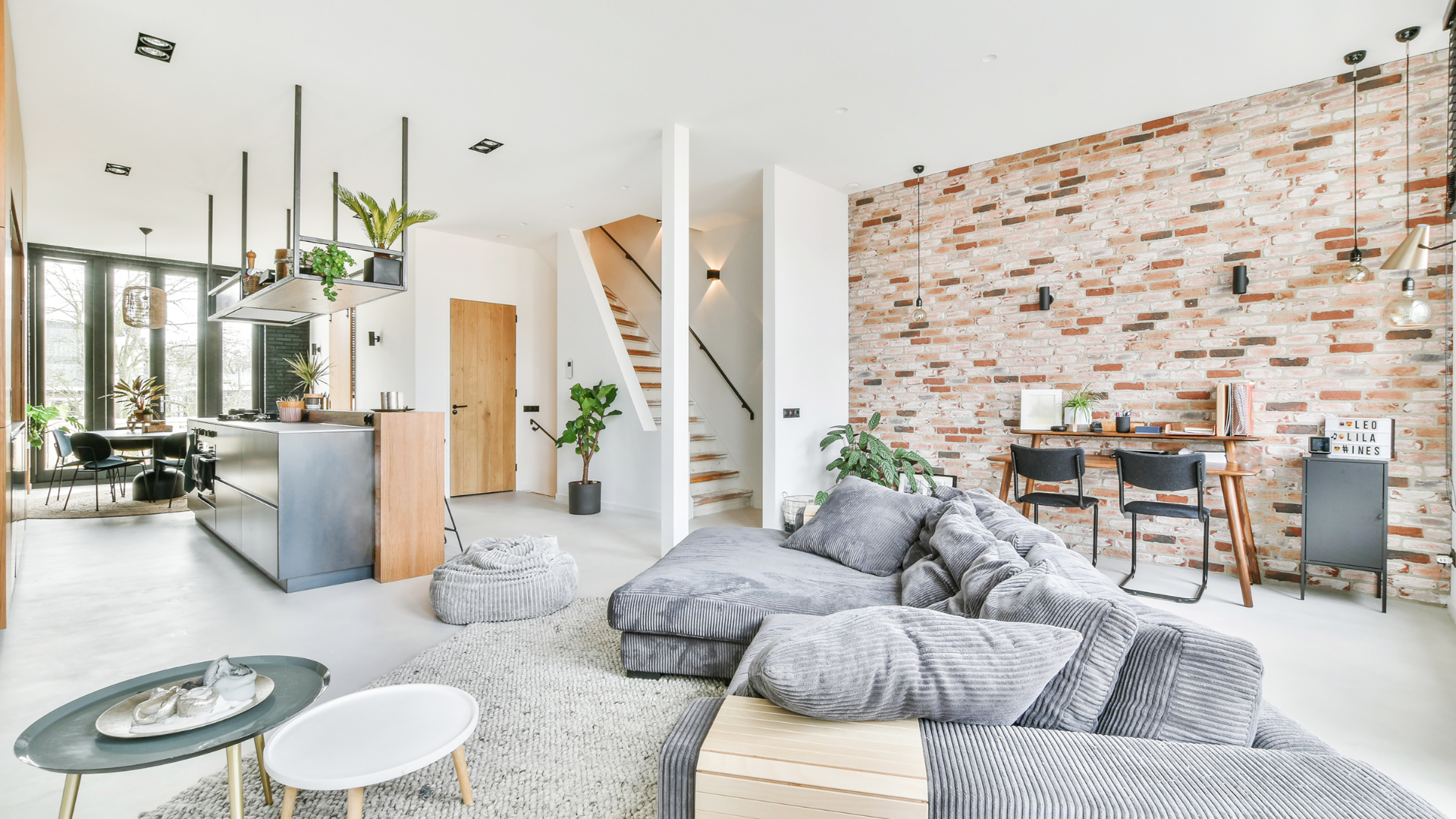 A living room with a couch , table , chairs and a brick wall.