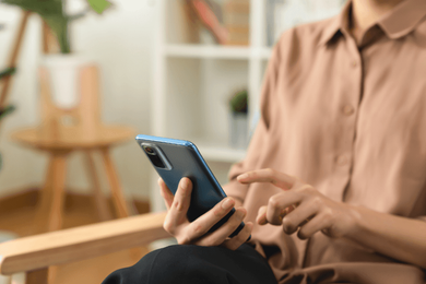 A woman is sitting in a chair using a cell phone.