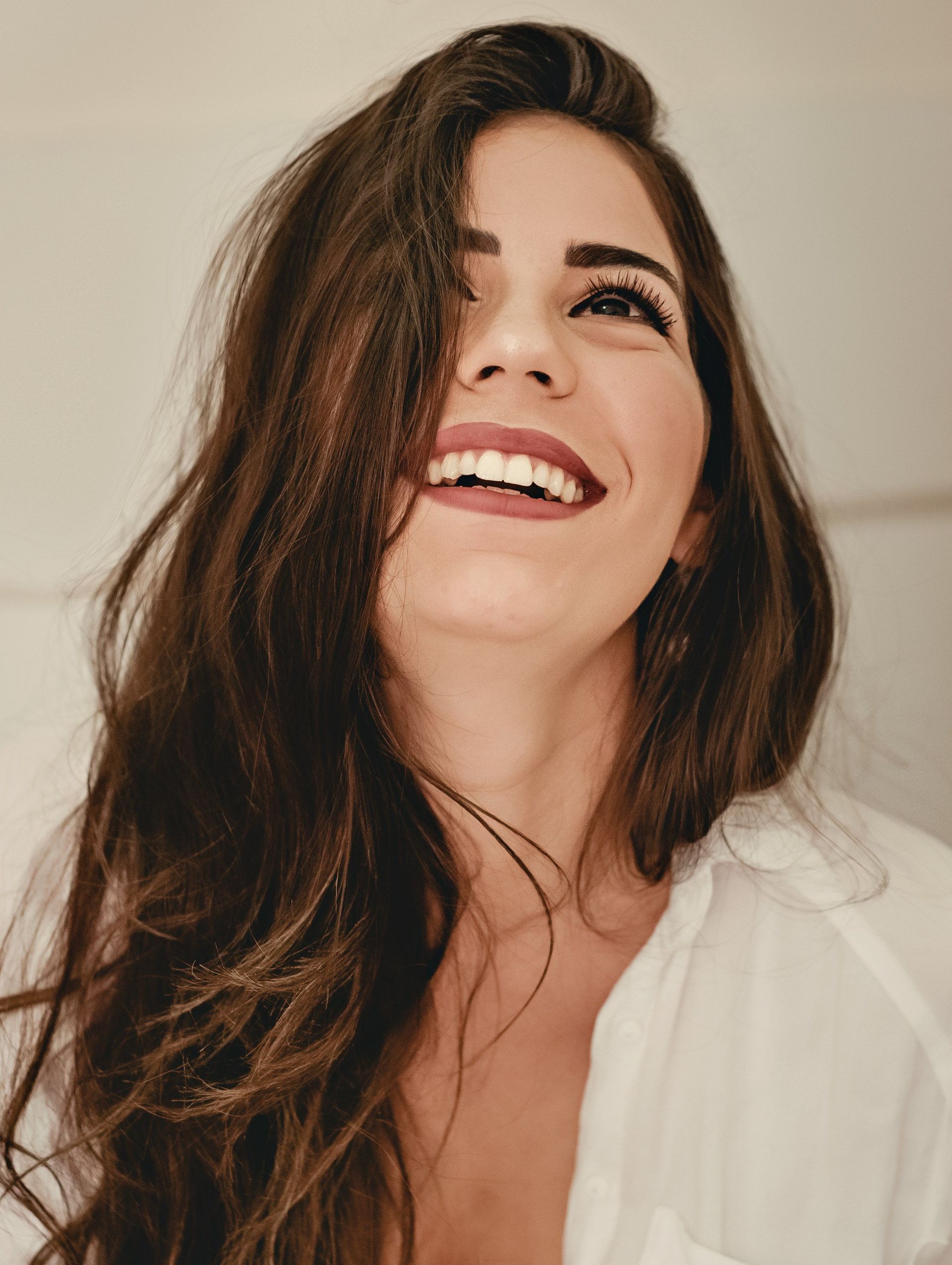 A woman with long hair is smiling and looking up at the camera.